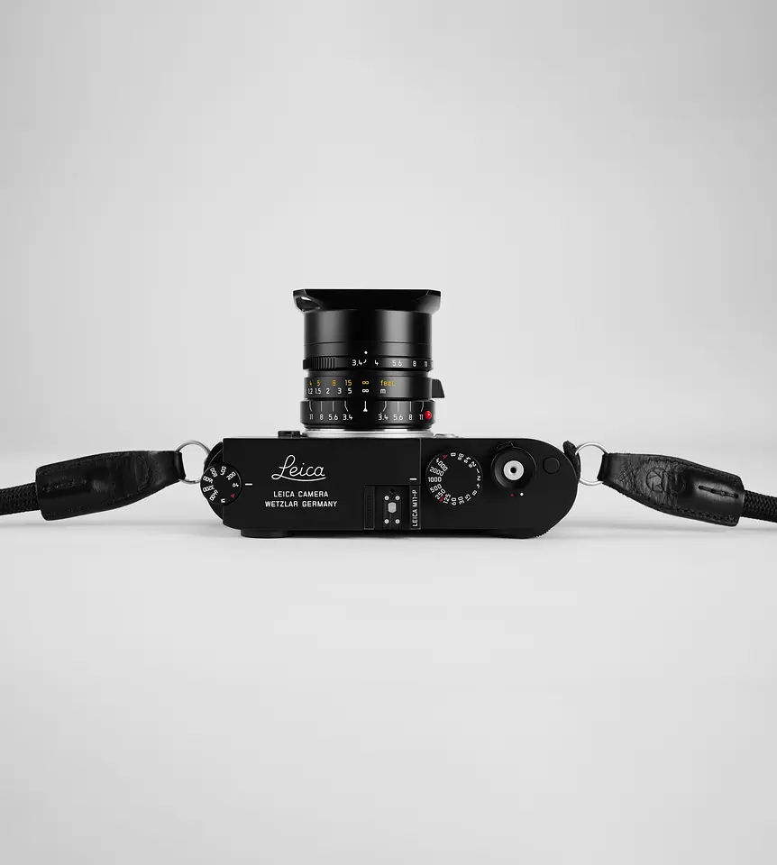 Leica M11-P mit Super-Elmar-M 1:3.4/21 ASPH. und Gegenlichtblende, Draufsicht auf grauem Grund